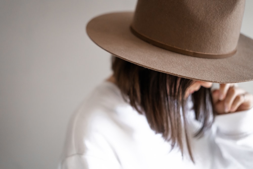 woman in white shirt wearing brown fedora hat