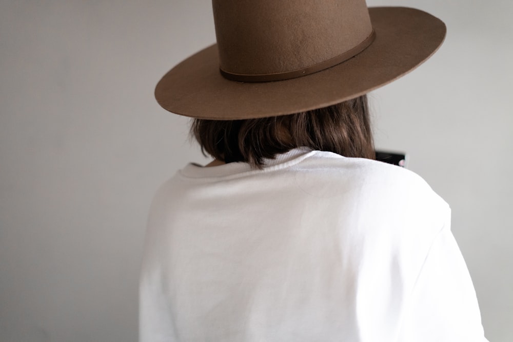 woman in white shirt wearing brown fedora hat