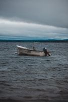 A small motorboat floats on a vast body of water under a cloudy sky. The boat, bearing the number 140251, is unoccupied and appears to be gently swaying with the movement of the waves.