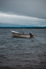 A small motorboat floats on a vast body of water under a cloudy sky. The boat, bearing the number 140251, is unoccupied and appears to be gently swaying with the movement of the waves.