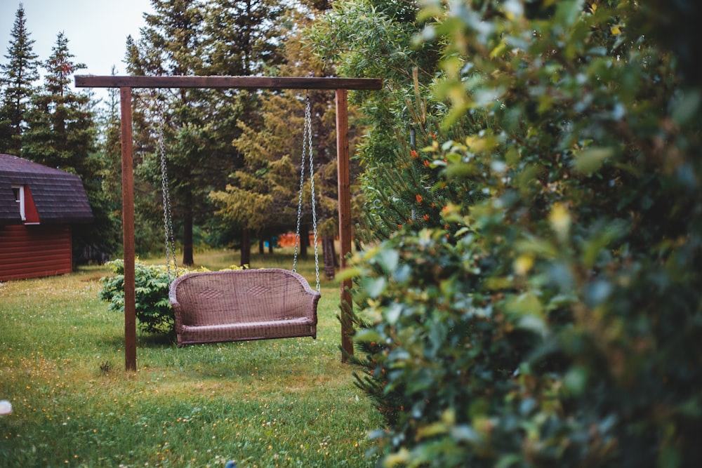 brown wooden swing near green leaf tree during daytime