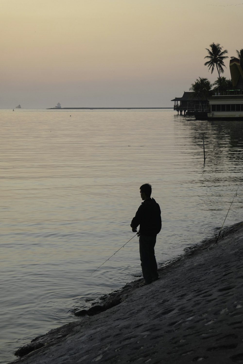 man in black jacket fishing on sea during daytime