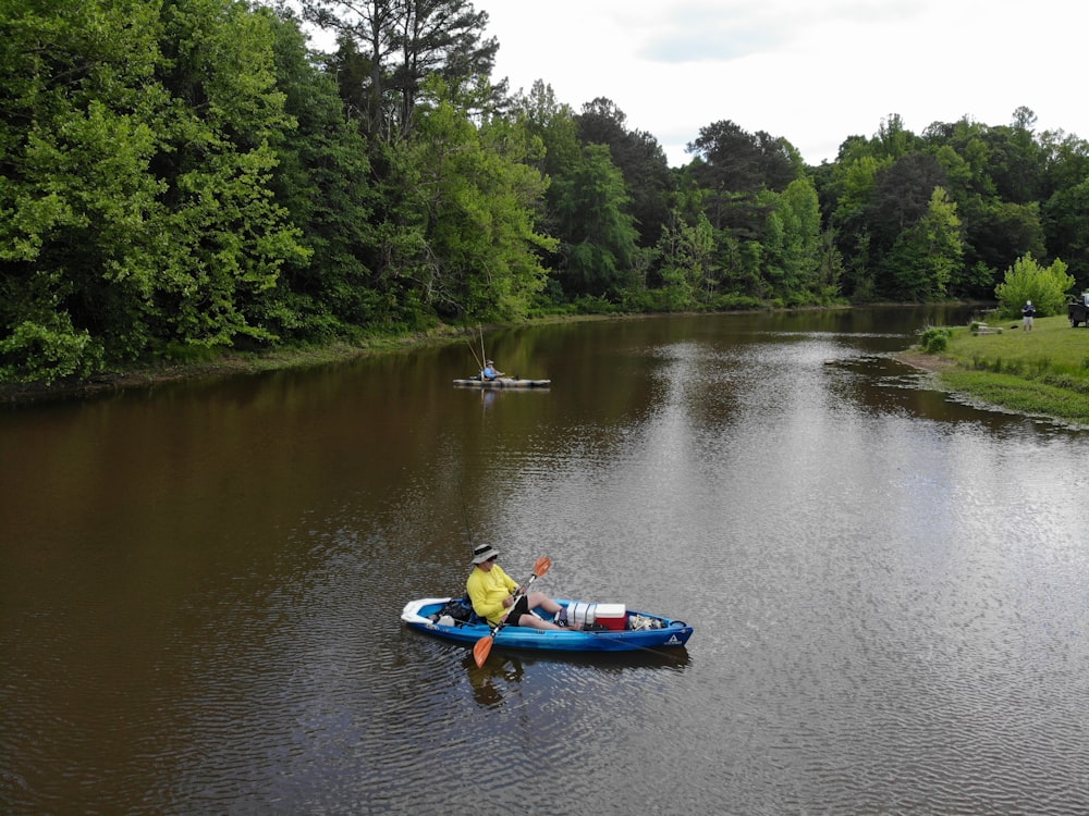 person riding blue kayak on lake during daytime