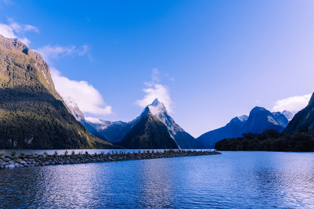 body of water near mountain under blue sky during daytime