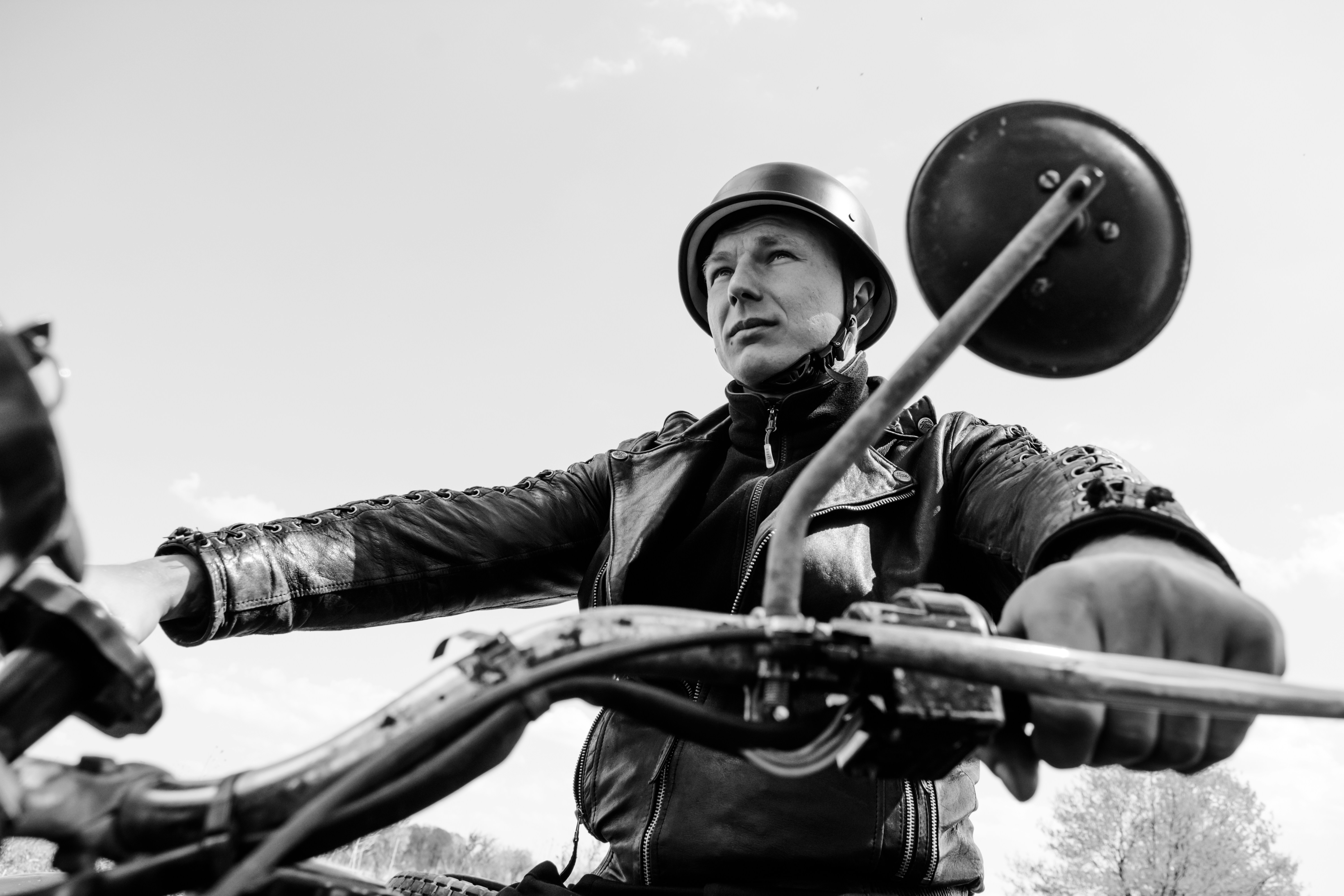 grayscale photo of man in black jacket and helmet holding rifle