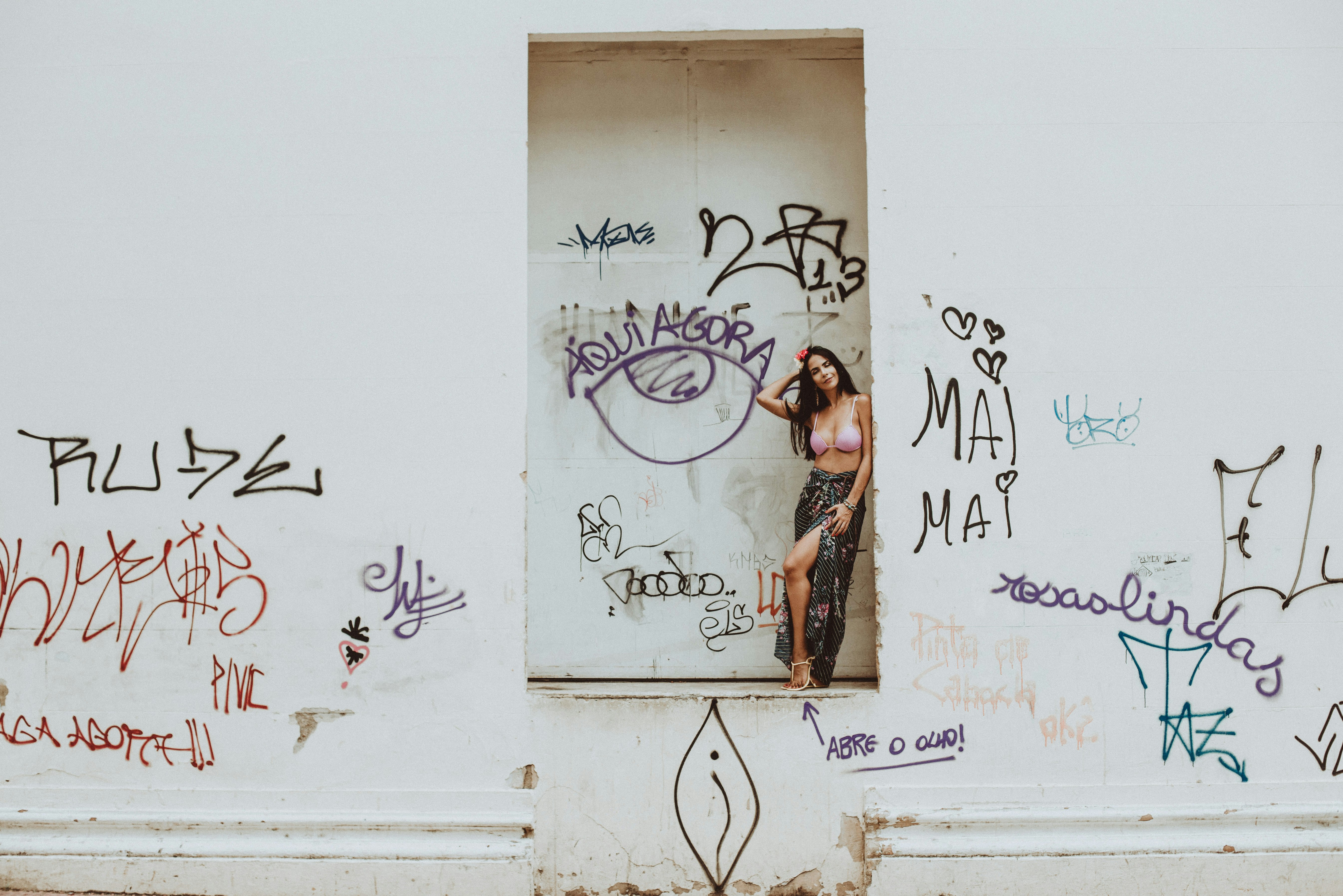 woman in brown and black dress standing beside white wall with graffiti