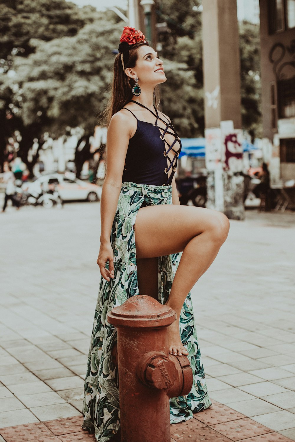 woman in blue and white floral spaghetti strap top and blue denim shorts standing on brown