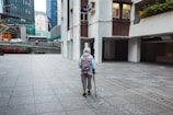 A patient walking confidently with a cane outdoors during hip replacement recovery.
