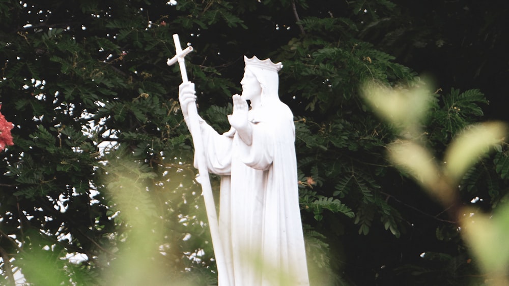 white angel statue near green leaf tree