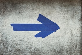 blue arrow sign on gray textile