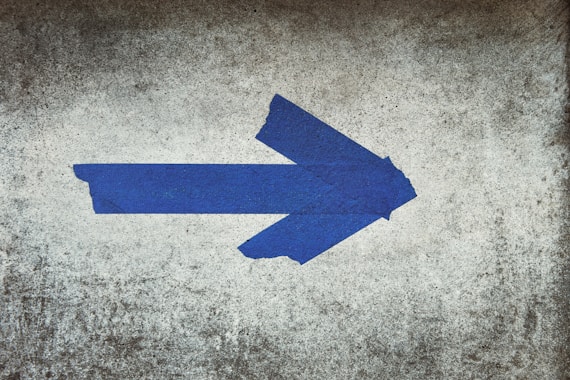blue arrow sign on gray textile