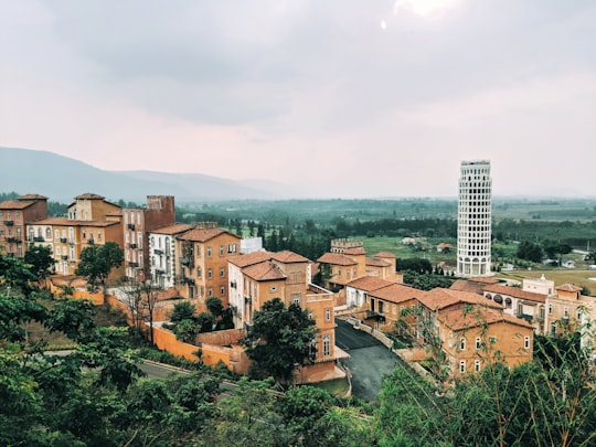 brown and white concrete buildings near green trees under white clouds during daytime in Nakhon Ratchasima Thailand