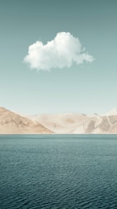 brown mountains beside blue sea under blue sky during daytime