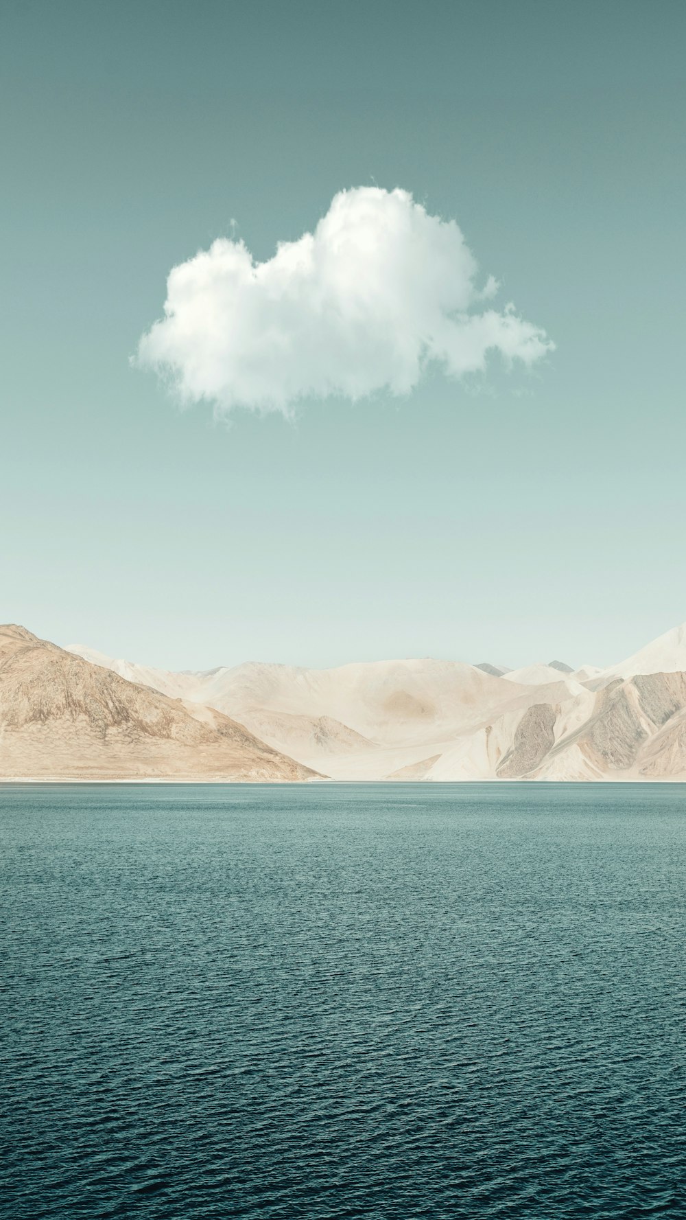 Braune Berge neben blauem Meer unter blauem Himmel tagsüber