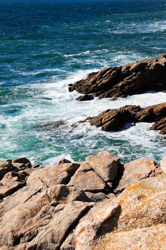 brown rocky shore with ocean waves crashing on rocks during daytime in Quiberon France