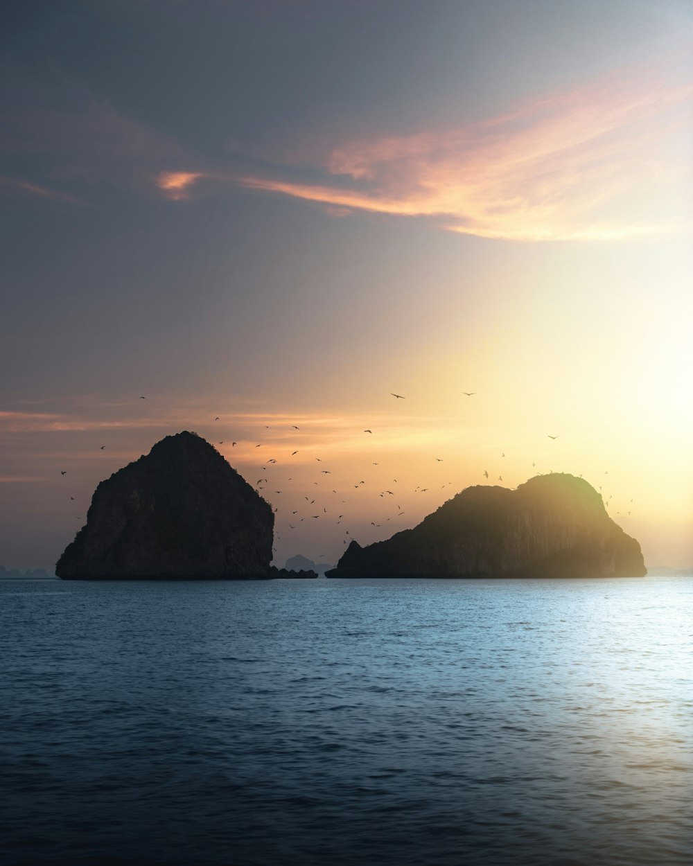 silhouette of rock formation on sea during sunset