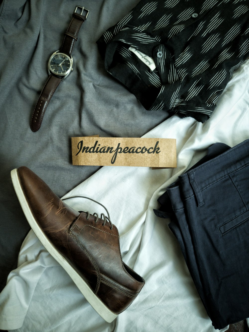 jeans blu denim accanto cinturino in pelle marrone argento rotondo orologio analogico