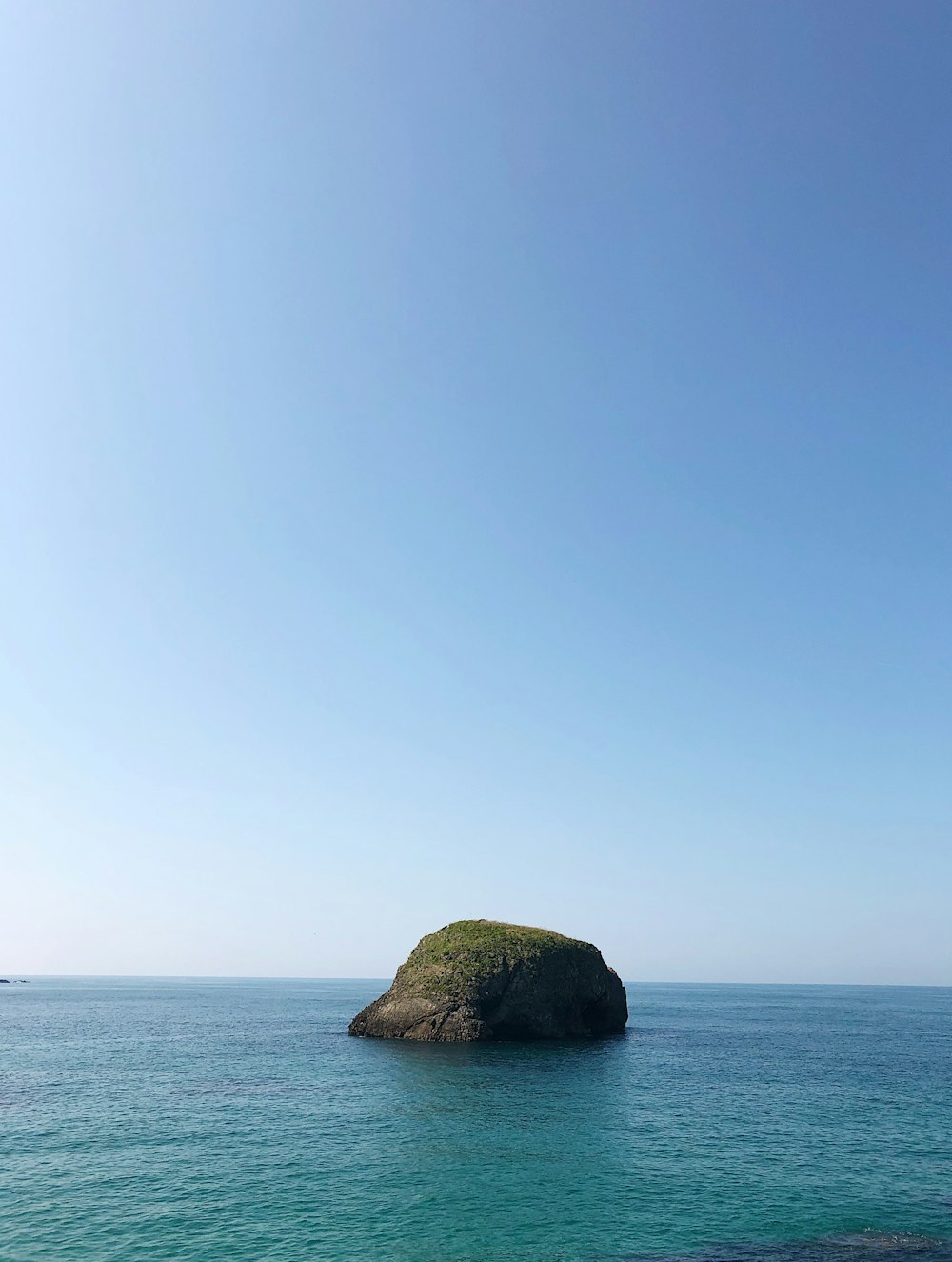 brown rock formation on blue sea under blue sky during daytime