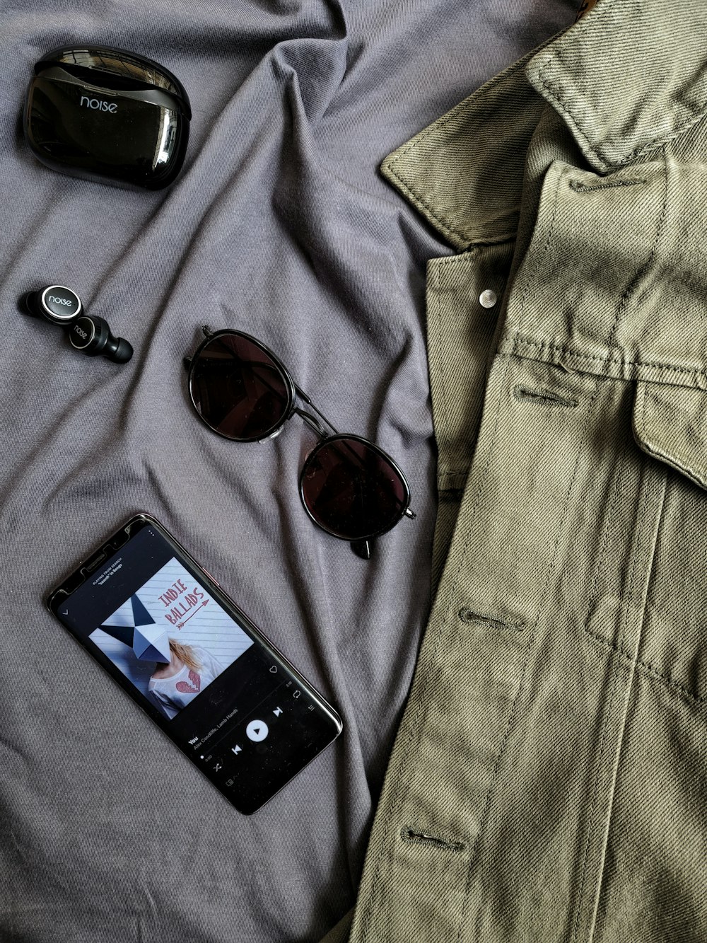 茶色のフレームのサングラスとグレーのデニムのボタンアップシャツの横にある黒いiPhone 4