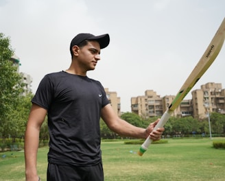 man in black crew neck t-shirt and black cap holding baseball bat