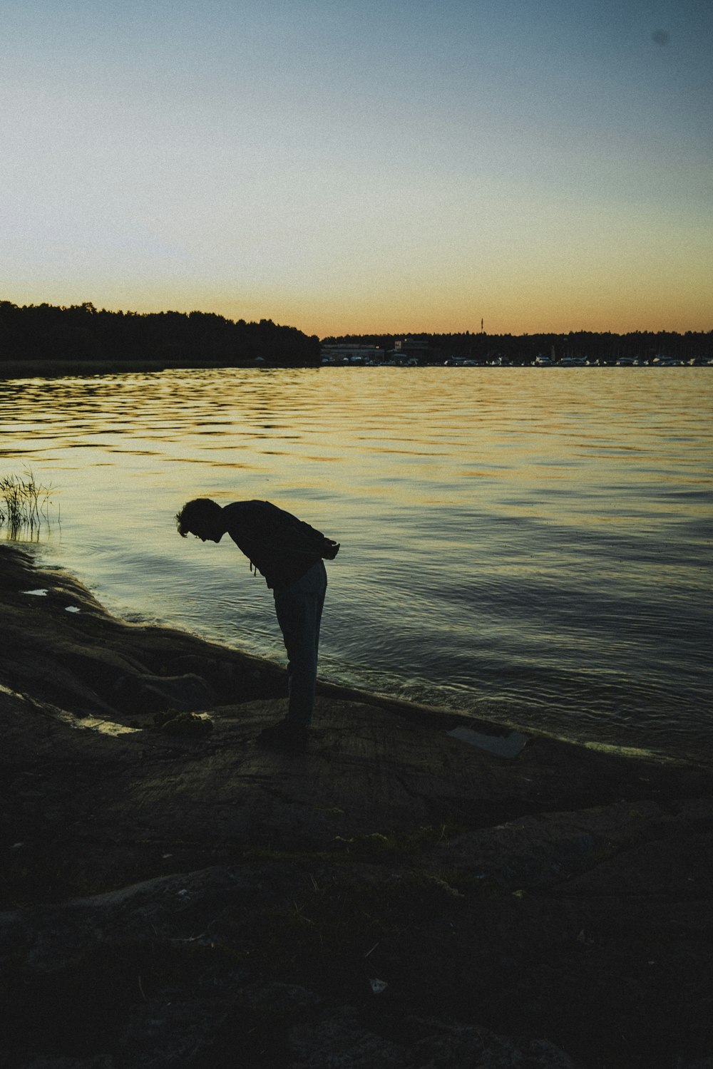 man in black jacket and gray pants standing on brown wooden dock during daytime