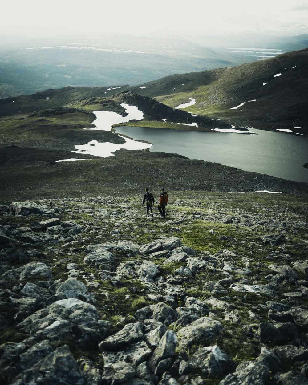 2 people walking on rocky shore during daytime