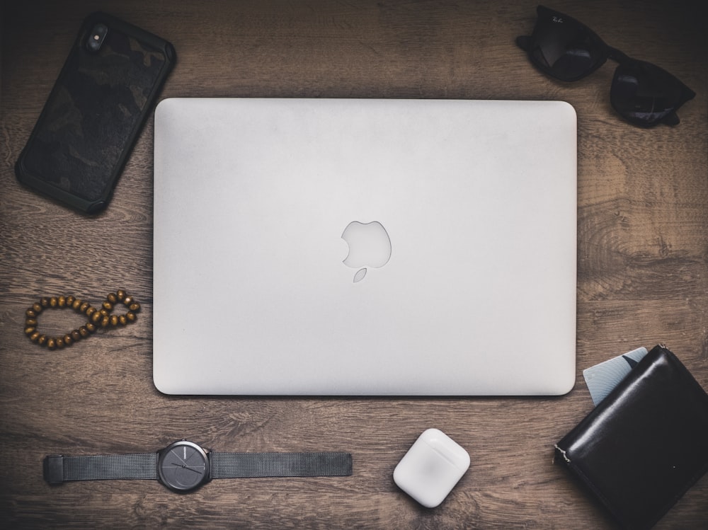 silver macbook beside black and silver round analog watch