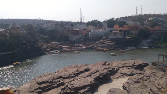 brown rocky mountain beside body of water during daytime in Omkareshwar India