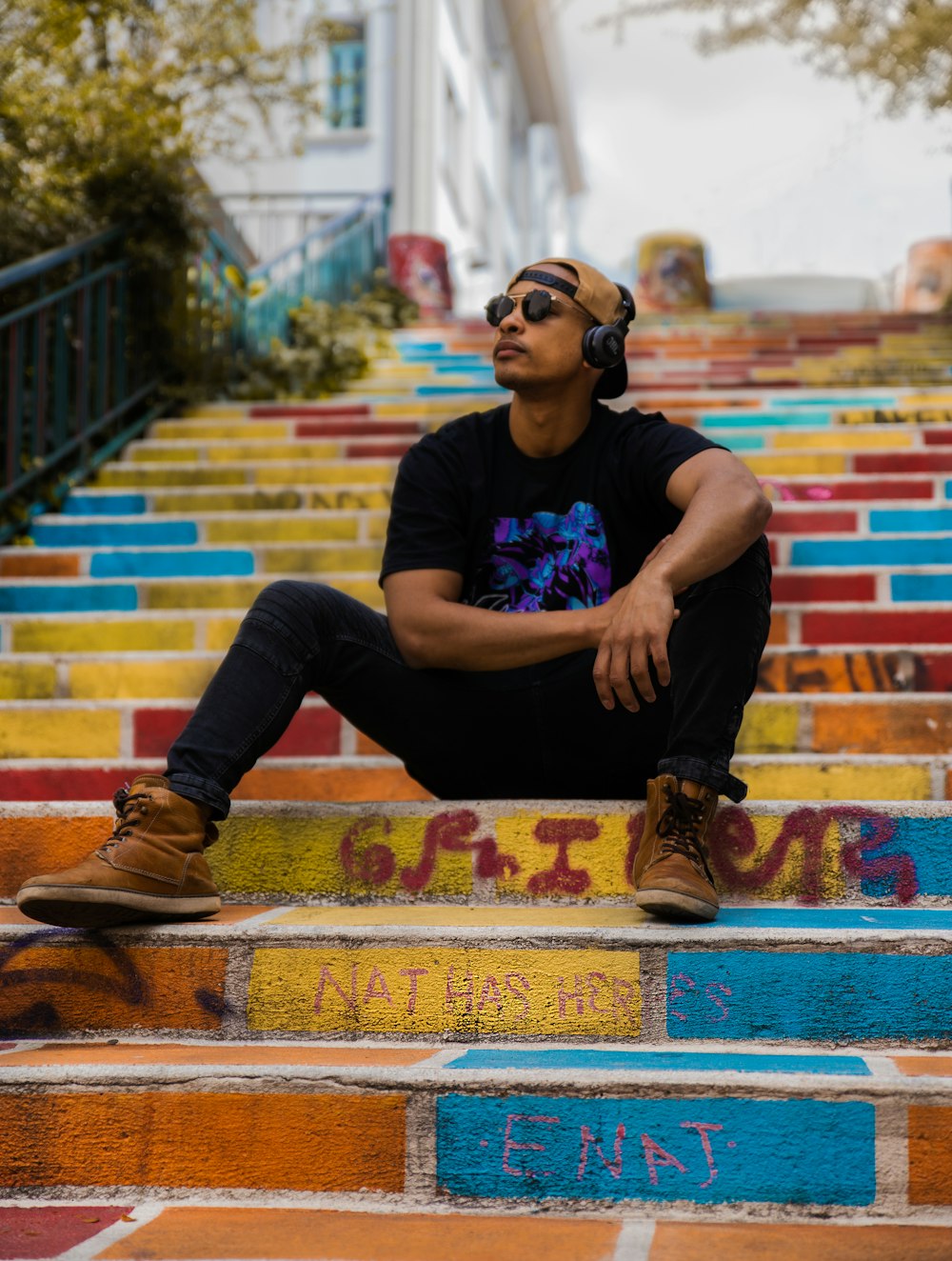 man in black crew neck t-shirt and black pants sitting on brown and red concrete