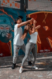 woman in white t-shirt and blue denim jeans standing beside wall with graffiti