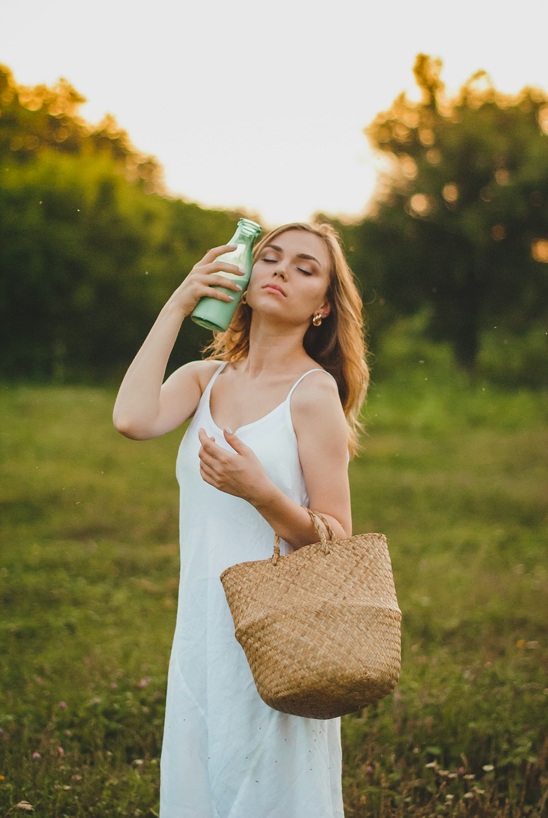 woman in white tank top holding green and blue plastic bottle