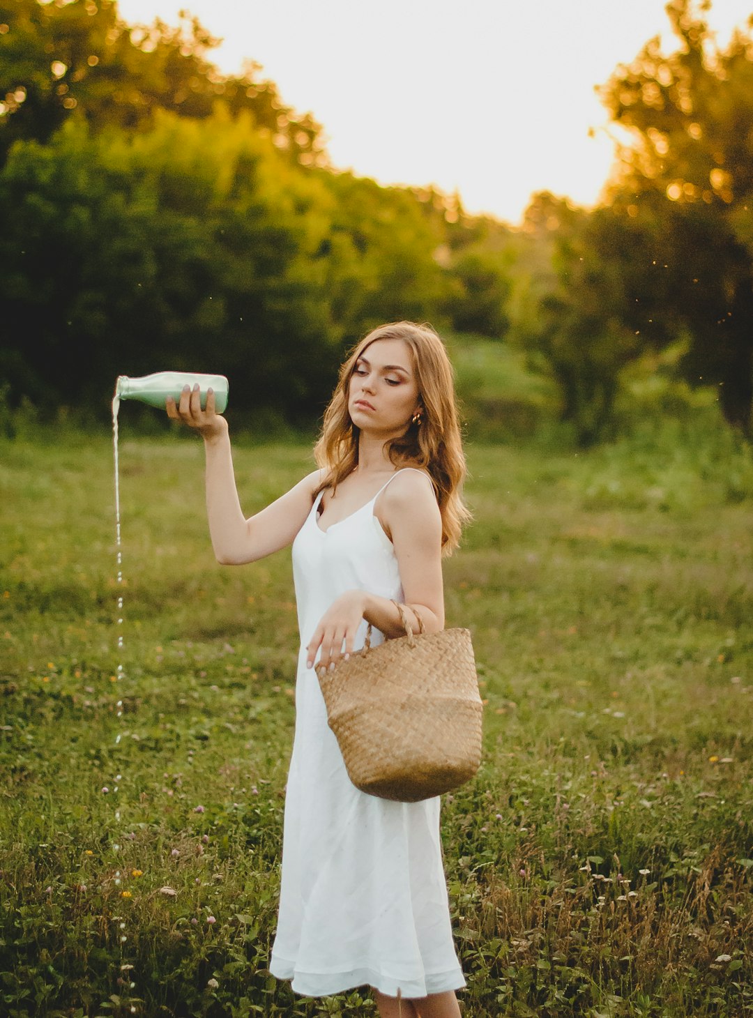 woman in white tank dress holding white ceramic mug standing on green grass field during daytime