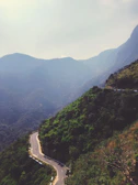 A panoramic view of winding roads cutting through lush green hills.