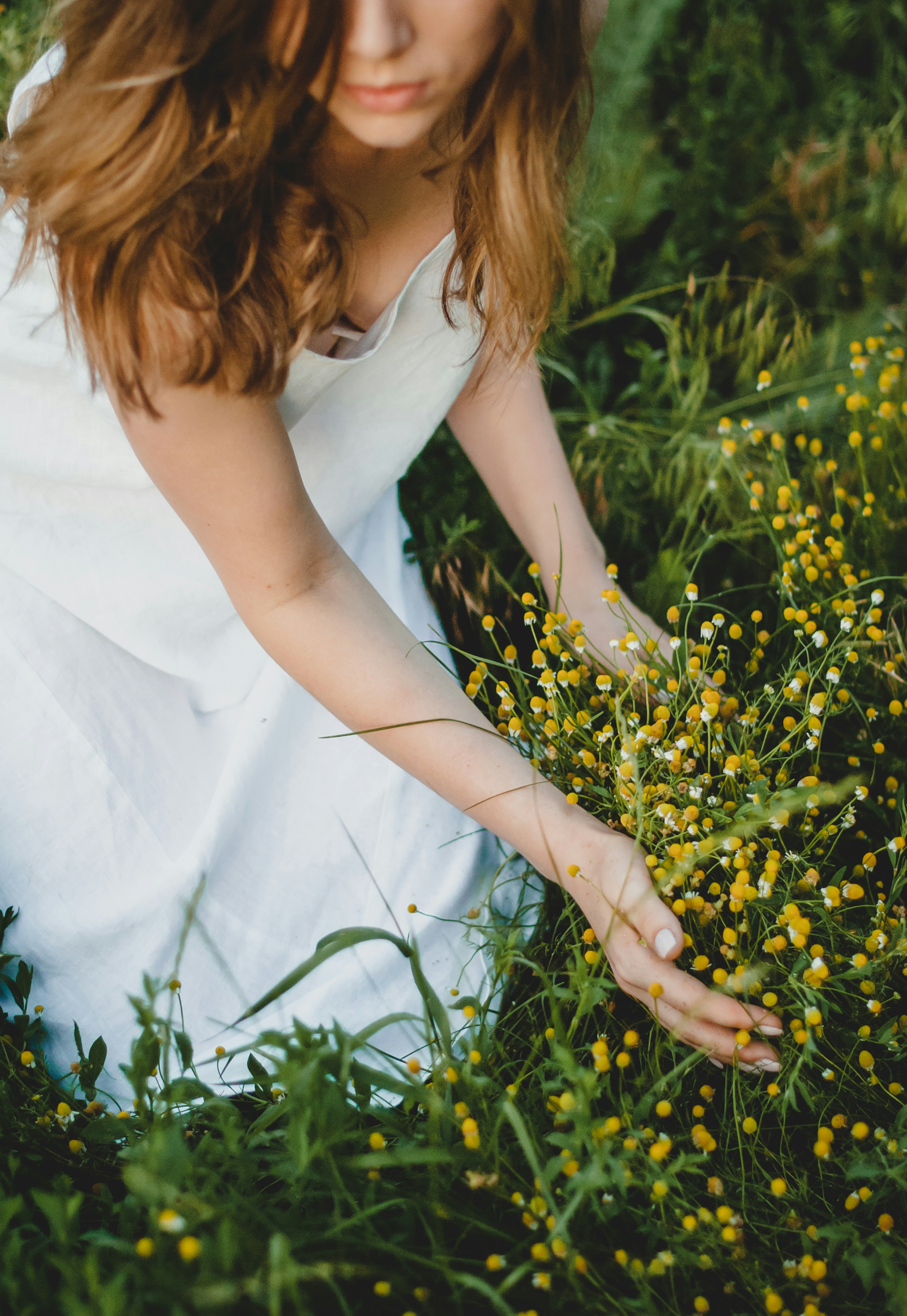 woman in white sleeveless dress standing on yellow flower field during daytime