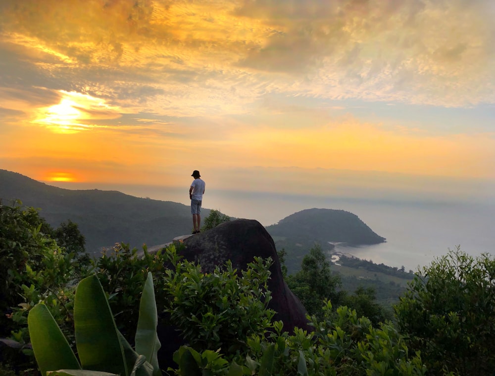 man standing on top of mountain during sunset