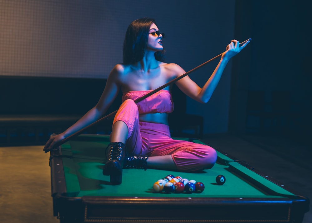 woman in purple tank top and black pants playing billiard