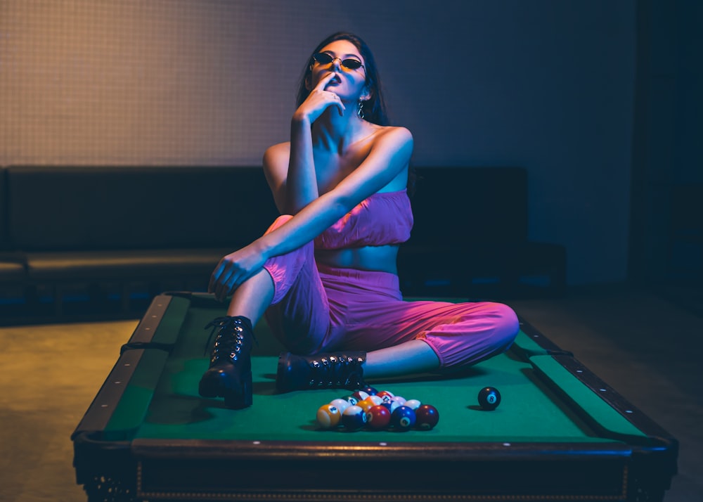 woman in purple dress sitting on billiard table