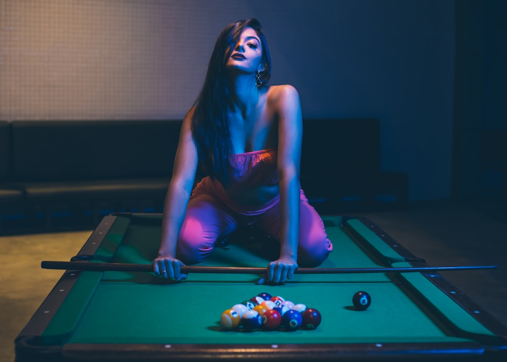 woman in purple tank top and pink leggings sitting on billiard table