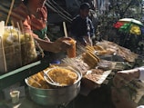 A cheerful vendor serving traditional Brazilian street food to smiling people on a sunny day.