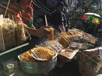 Smiling vendors serving freshly made street food to eager attendees on a sunny day.