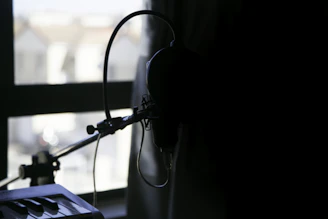 A dimly lit urban rooftop at night with a microphone and headphones set against a city skyline.