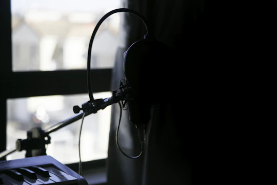 A dimly lit urban rooftop at night with a microphone and headphones set against a city skyline.