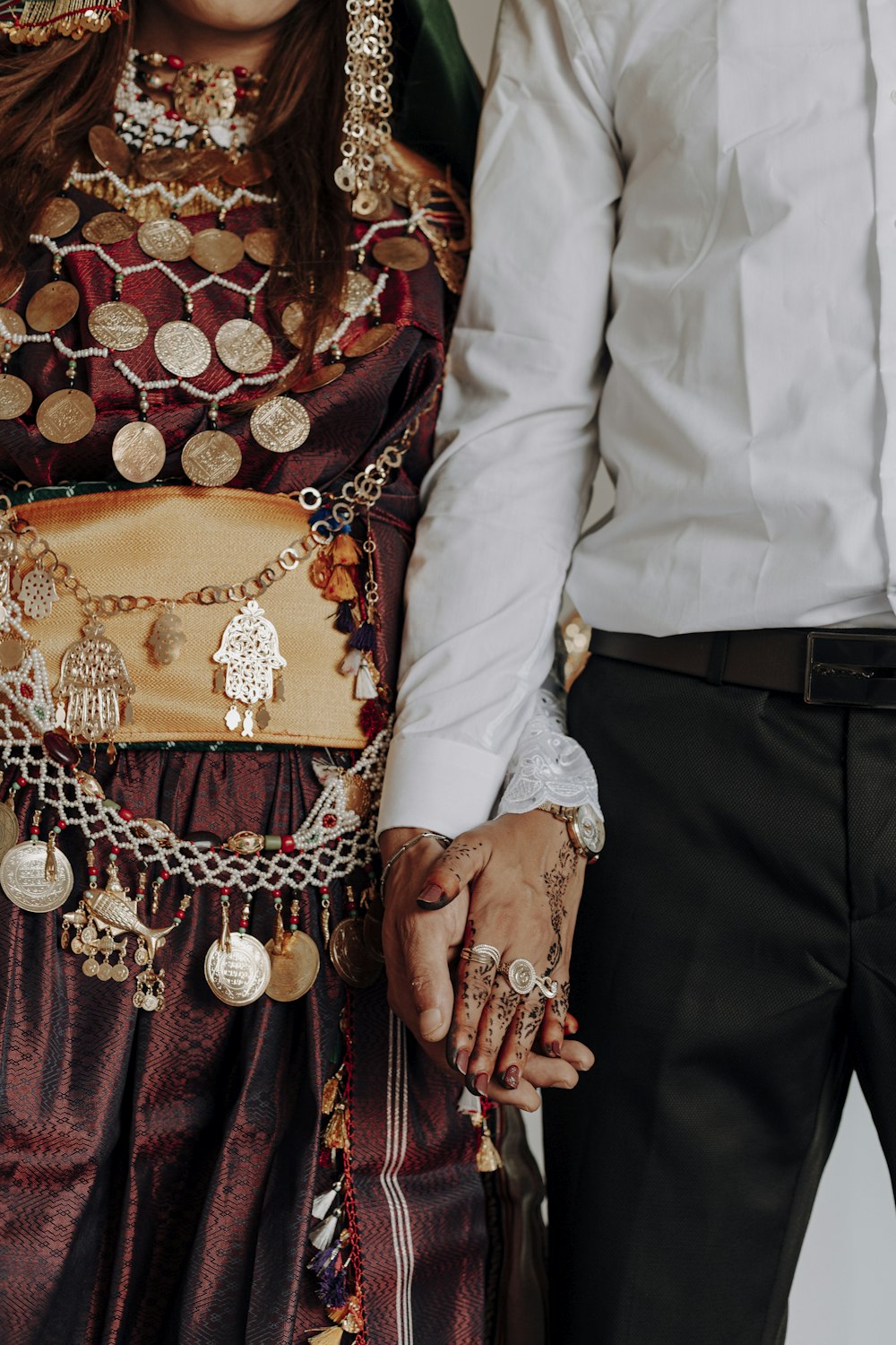 man in white dress shirt and black pants holding woman in red and gold dress