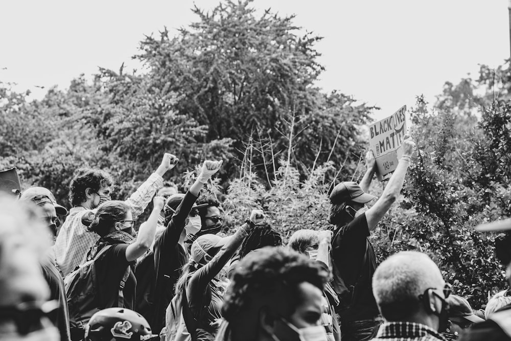 grayscale photo of people raising their hands