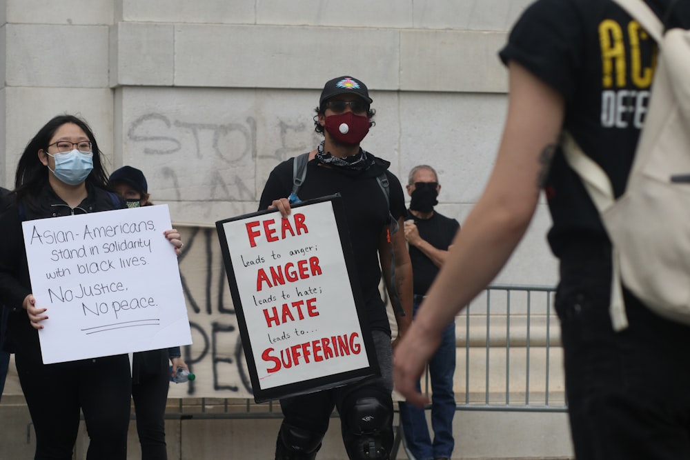 man in black t-shirt and black pants holding white and red signage