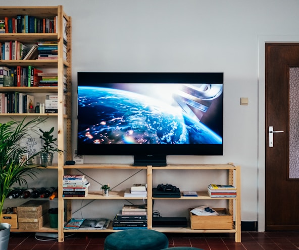 black flat screen tv turned on near brown wooden shelf