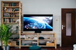 black flat screen tv turned on near brown wooden shelf