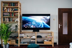 black flat screen tv turned on near brown wooden shelf