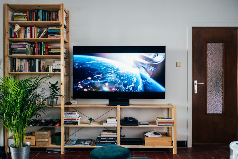 black flat screen tv turned on near brown wooden shelf