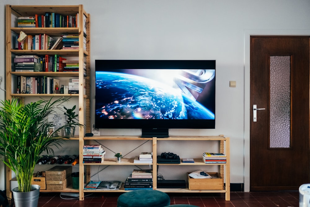 Televisor de pantalla plana negro encendido cerca de un estante de madera marrón